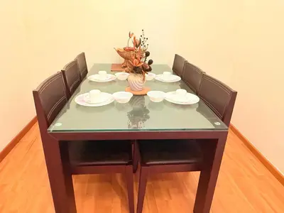 a table with four chairs and a vase with flowers on it at Park view Apartment near klcc in Kuala Lumpur