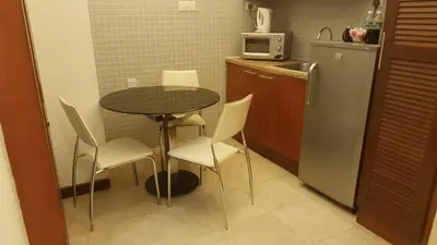 a small kitchen with a table and chairs and a refrigerator at Studio apartment in Kuala Lumpur