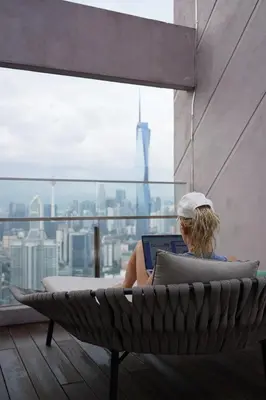 a woman sitting in a hammock with a laptop on a building at Riveria City Kuala Lumpur By Nest Suites in Kuala Lumpur