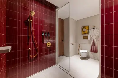 a red tiled bathroom with a shower and a toilet at Kimpton Naluria Kuala Lumpur by IHG in Kuala Lumpur