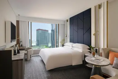 a hotel room with a white bed and a large window at Kimpton Naluria Kuala Lumpur by IHG in Kuala Lumpur