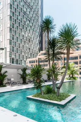 a swimming pool with palm trees in a city at Acappella Kuala Lumpur City Centre in Kuala Lumpur