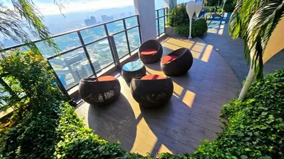 a balcony with four chairs and a view of the city at Trion KL Service Suite - Modern City Stay with Pool & Gym in Kuala Lumpur