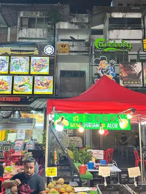 a man is sitting in front of a food stand at SS Grey House Bukit Bintang in Kuala Lumpur