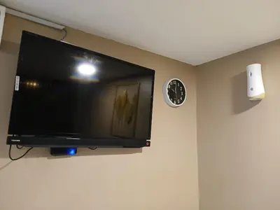a flat screen tv hanging on a wall with a clock at SS Grey House Bukit Bintang in Kuala Lumpur