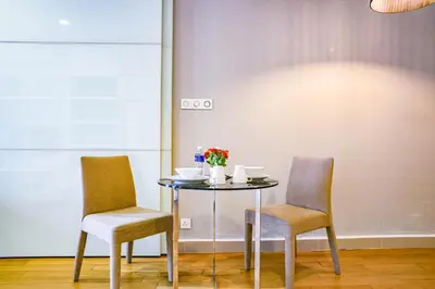 a table with two chairs and a table with flowers on it at Sama Suites at Platinum KLCC Bukit Bintang in Kuala Lumpur