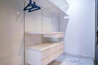 a closet with white cabinets and a glass shelf at Sama Suites at Platinum KLCC Bukit Bintang in Kuala Lumpur