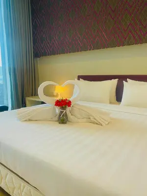 a white bed with a vase of flowers on it at The Platinum Suites KLCC in Kuala Lumpur
