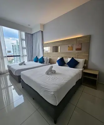 two beds in a hotel room with blue pillows at The Signature Suites at Robertson Bukit Bintang in Kuala Lumpur