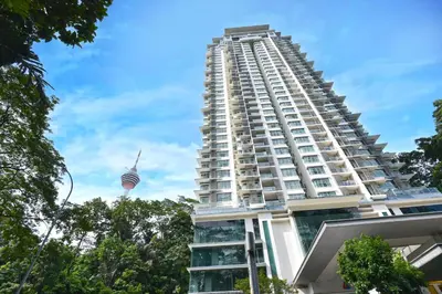 a tall white building with a tower in the background at Palette Bukit Bintang Formerly Suasana Suites in Kuala Lumpur