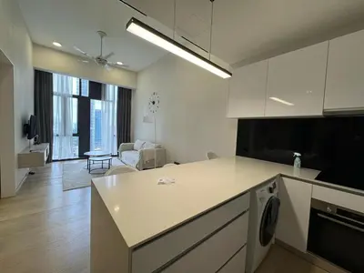 a kitchen with white cabinets and a living room at Star Residences One in Kuala Lumpur
