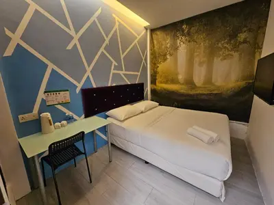 a bedroom with a bed and a desk and a painting at V Garden Hotel by Minsu in Kuala Lumpur