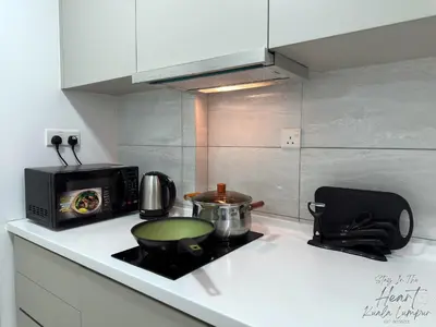 a kitchen with a stove with a pot and a microwave at Cozy Minimalist Condo In The Heart of Kuala Lumpur City 1BR in Kuala Lumpur