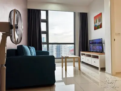 a living room with a blue couch and a large window at Cozy Minimalist Condo In The Heart of Kuala Lumpur City 1BR in Kuala Lumpur