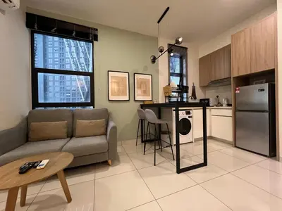 a kitchen and living room with a couch and a table at Regalia Residences and suits By Comfortcorner in Kuala Lumpur