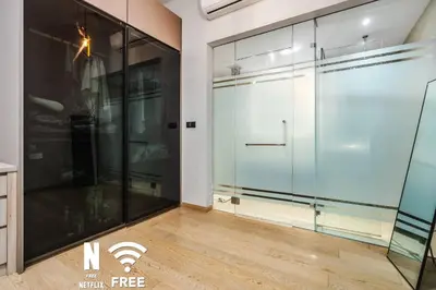 a glass pivot door in a room with a wooden floor at Comfy 1 BR unit 2 mins from KLCC in Kuala Lumpur