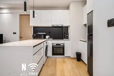 a kitchen with white cabinets and a wooden floor at Comfy 1 BR unit 2 mins from KLCC in Kuala Lumpur
