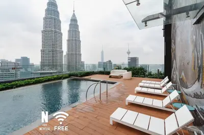 a pool on the roof of a building with tall skyscrapers at 1BR| Rooftop Twin Towers View l Near LRT in Kuala Lumpur