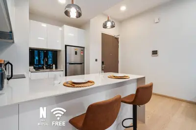 a kitchen with a counter with two chairs and a table at 1BR| Rooftop Twin Towers View l Near LRT in Kuala Lumpur