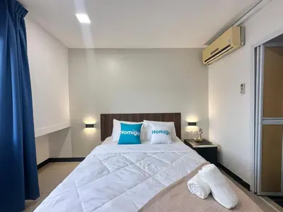 a bedroom with a large white bed with blue pillows at Homigo - PWTC in Kuala Lumpur