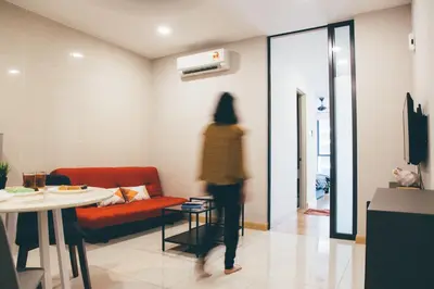 a person walking through a room with a table and chairs at KL Gateway Bangsar by Sleepy Bear in Kuala Lumpur