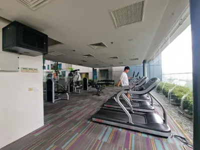 a gym with a row of treadmills and a man in the background at Summer Luxury Suites KlCC by ATIQ in Kuala Lumpur
