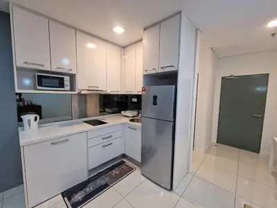 a kitchen with white cabinets and a stainless steel refrigerator at Summer Luxury Suites KlCC by ATIQ in Kuala Lumpur