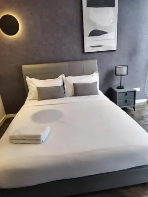 a large white bed in a bedroom with a lamp at Scarletz Suites KLCC by IH in Kuala Lumpur