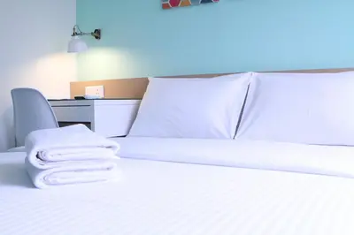a bed with white sheets and towels on it at Hotel 1000 Miles in Kuala Lumpur