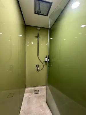 a bathroom with a shower with green walls at Sleep in the Sky KLCC View in Kuala Lumpur