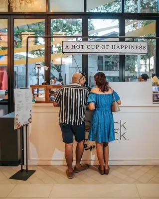 a man and a woman standing in front of a hot cup of happiness at Scarletz Luxury Suites KLCC in Kuala Lumpur