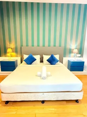 a bedroom with a large white bed with blue pillows at The Platinum KLCC By Homestay in Kuala Lumpur