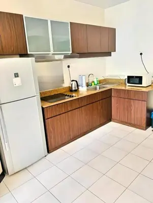 a kitchen with wooden cabinets and a white refrigerator at Seri Bukit Ceylon Dreamy Destiny luxe Suites in Kuala Lumpur