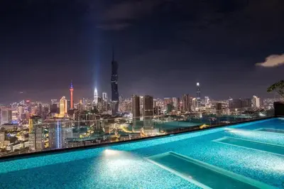 a view of a city skyline at night from a swimming pool at Maxhome Cozy at Riveria KL in Kuala Lumpur
