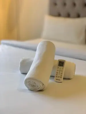 a rolled up towel and a remote control on a bed at KLCC The Mews Luxury suites Malaysia in Kuala Lumpur