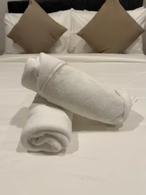 a pile of white towels on a bed at Cyelonz Suites in Kuala Lumpur