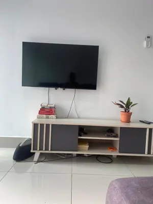 a living room with a tv on a white wall at Simple Comforts KL Shared apt in Kuala Lumpur