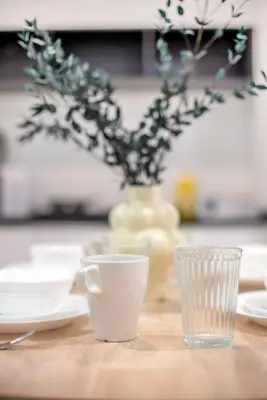a table with two cups and a vase with flowers at Neu Suites Ampang near Gleneagles in Kuala Lumpur