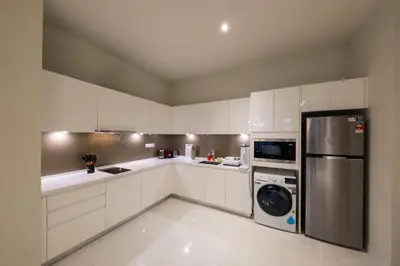 a kitchen with white cabinets and a washer and dryer at La Gente X Pavilion Embassy Serviced Suites in Kuala Lumpur