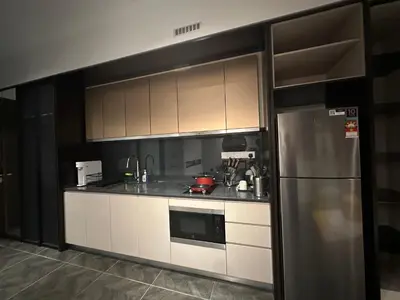 a kitchen with white cabinets and a stainless steel refrigerator at SKYLINE HOME BY SCARLETZ SUITEs KLCC in Kuala Lumpur