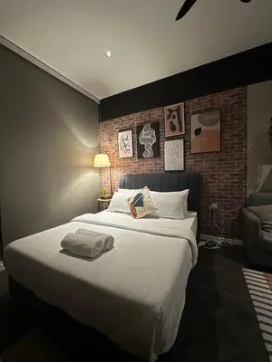 a bedroom with a large white bed with a brick wall at SKYLINE HOME BY SCARLETZ SUITEs KLCC in Kuala Lumpur