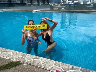 two women in the water holding a sign in a swimming pool at Female Hostel wakakapacker in Kuala Lumpur
