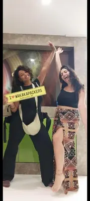 two women are standing in front of a poster at Female Hostel wakakapacker in Kuala Lumpur
