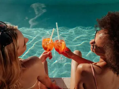 two women sitting next to a swimming pool holding drinks at Female Hostel wakakapacker in Kuala Lumpur