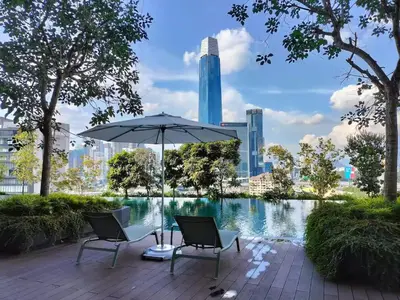 a patio with two chairs and an umbrella next to a pond at 7Pax Muji Continew KL Centre View 10mins to TRX KLCC IKEA in Kuala Lumpur