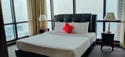a bed with two red pillows in a room with windows at Urban Suite At Times Square KL in Kuala Lumpur
