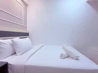a white bed with white pillows and a towel on it at Colony Greenfield Suites Klcc in Kuala Lumpur