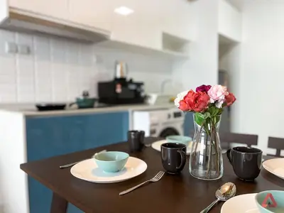 a table with plates and a vase of flowers on it at Residensi Continew 5 min walk MRT Train, TRX KL City Centre view Apartment in Kuala Lumpur