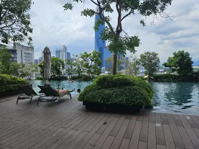 a person sitting in a chair next to a body of water at Residensi Continew 5 min walk MRT Train, TRX KL City Centre view Apartment in Kuala Lumpur