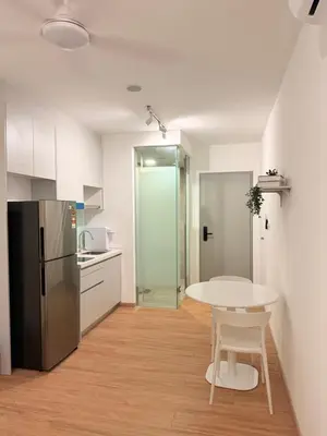 a white kitchen with a table and a refrigerator at COzy Suite KL Sentral By Riveria City in Kuala Lumpur